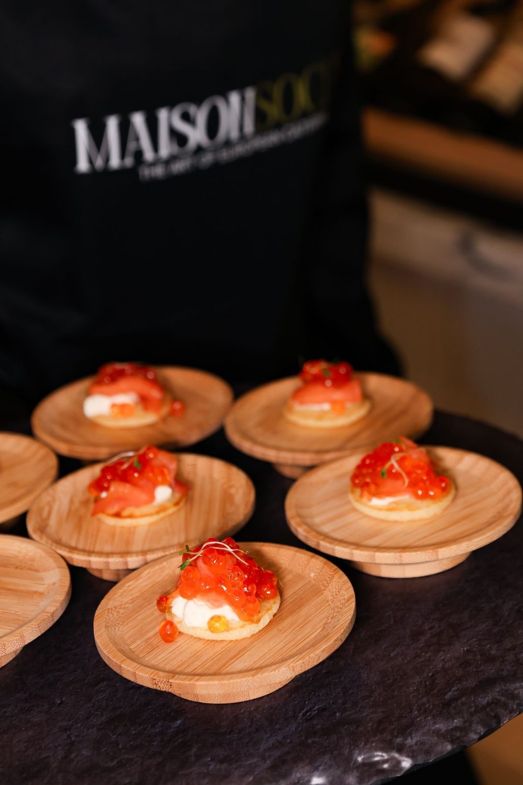 Server in a Maison Social apron with passed canapes