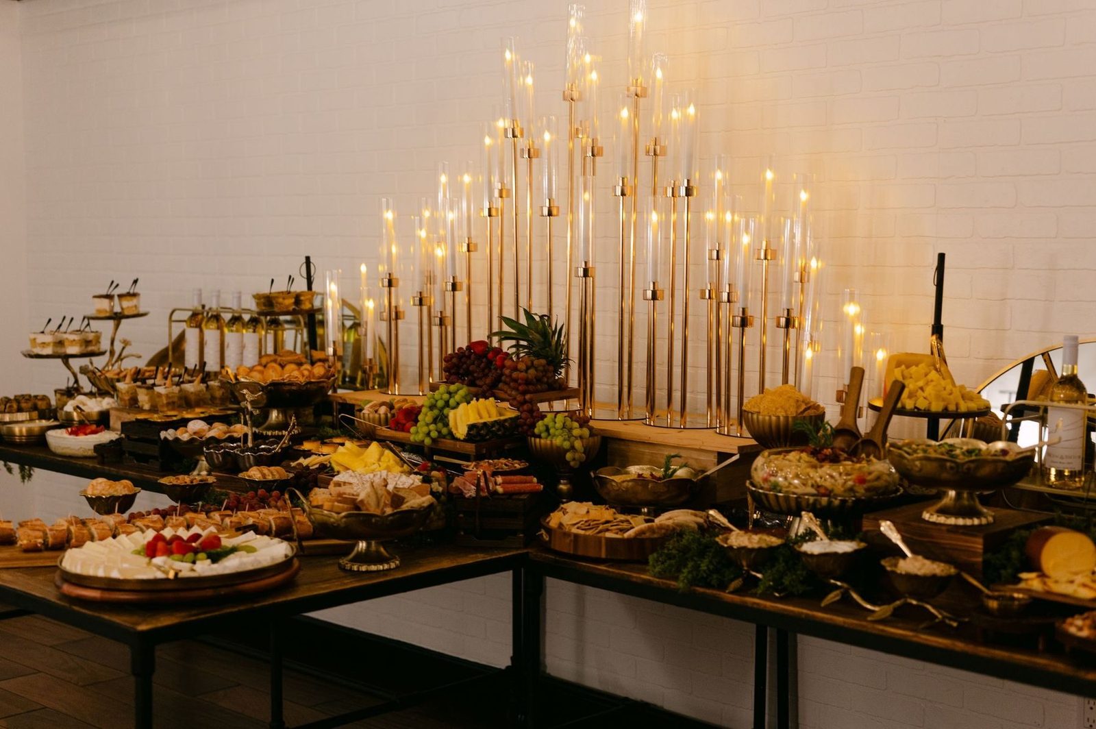 Candlelit grazing table under a wall of gold candelabra